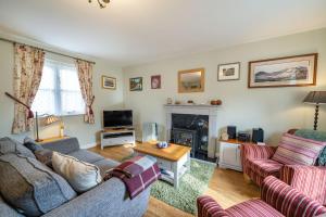 a living room with two couches and a fireplace at Amber Cottage in Holker