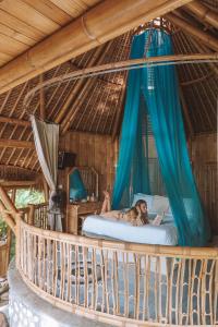 Eine Frau, die auf einem Bett in einer Hängematte liegt. in der Unterkunft La royale Romantic Bamboo Villas in Klungkung