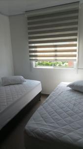 1 Schlafzimmer mit 2 Betten und einem Fenster mit Jalousien in der Unterkunft Excelente Apartamento en Girardot in Girardot