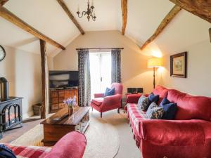a living room with red furniture and a fireplace at Stockwell Hall Cottage in Sebergham