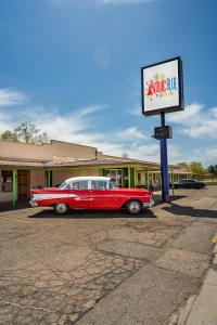 um velho carro vermelho estacionado em frente a um motel em The Atomic Blue Motor-Inn em Monticello