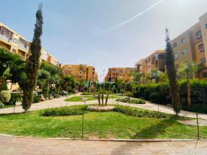 a park in a city with palm trees and buildings at Un nouvel appartement-5 min de l'aéroport in Marrakech