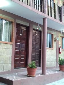 un edificio con dos puertas marrones y dos macetas en Hotel Villas Kerendarhú, en Bernal