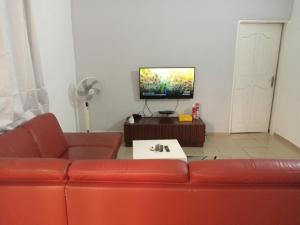 a living room with a red couch and a flat screen tv at HEBERTOGO TOKOIN CASABLANCA in Lomé