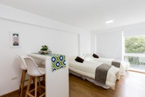 2 łóżka w białym pokoju ze stołem i krzesłami w obiekcie Pacífico Apartamentos Centro w mieście Ushuaia
