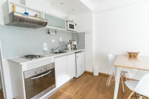 a small kitchen with white cabinets and a table at Pacífico Apartamentos Centro in Ushuaia