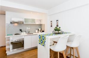 uma cozinha com armários brancos e uma mesa com cadeiras brancas em Pacífico Apartamentos Centro em Ushuaia