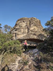 a woman is sitting on a rocky mountain at Pousada Duende Feliz in São Thomé das Letras