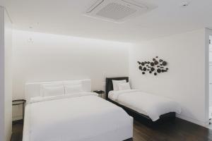 光州にあるACC デザイン ホテルの白い壁の客室内のベッド2台