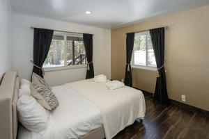 a bedroom with a white bed and two windows at Tahoe Paradise Chalet in South Lake Tahoe