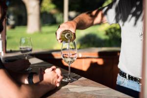 una persona que vierte vino en una copa de vino sobre una mesa en Similkameen Wild Resort & Winery Retreat, en Cawston