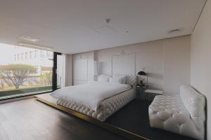 a white bedroom with a large bed and a chair at ACC Design Hotel in Gwangju