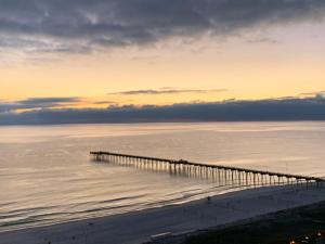 a pier stretches out into the ocean at sunset at Sunset Cove at Calypso III in Panama City Beach