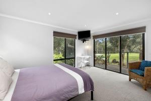 a bedroom with a bed and a chair and windows at Hidden Gem in Lorne