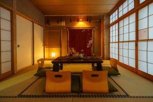 一棟貸切 Cozy inn Saki -Family & Cyclists Welcome - في ماتسوموتو: غرفة مع طاولة وكراسي في غرفة مع نوافذ