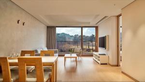 a living room with a dining table and a large window at Lotte Buyeo Resort in Buyeo