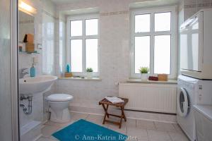 ein Badezimmer mit Waschbecken, Toilette und Waschmaschine in der Unterkunft Ferienhaus Am Ufer - Ferienwohnung Strandluft in Sassnitz