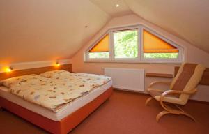 ein Schlafzimmer mit einem Bett und einem Stuhl sowie zwei Fenstern in der Unterkunft Ferienhaus Emma - Fewo 3 in Lohme
