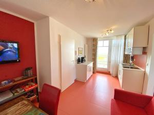 a living room with red walls and a kitchen at Appartements am Rondell Neddesitz, Appartement 306 in Neddesitz