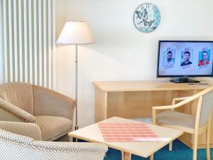 ein Wohnzimmer mit einem Tisch, einem TV und Stühlen in der Unterkunft Sassnitz - Villa Anna Villa Anna App 32 in Sassnitz