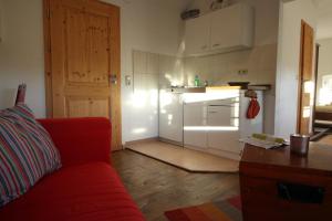ein Wohnzimmer mit einem roten Sofa und einer Küche in der Unterkunft Gutshof Dubnitz Gutshof Dubnitz -Ferienwohnung 4 " Anna " 