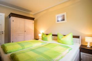 - une chambre dotée d'un lit avec des oreillers verts et jaunes dans l'établissement Lietzow Appartementhaus Möwe Haus Möwe - Ferienwohnung 2 "Fischmöwe", à Lietzow
