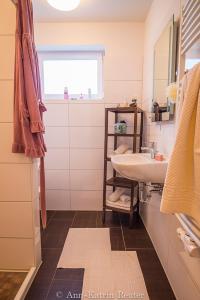 ein weißes Badezimmer mit Waschbecken und Fenster in der Unterkunft Lietzow Appartementhaus Möwe Haus Möwe - Ferienwohnung 2 "Fischmöwe" in Lietzow