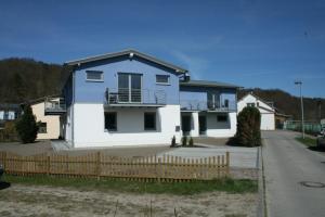 ein blau-weißes Haus mit einem Zaun in der Unterkunft Lietzow Appartementhaus Möwe Haus Möwe - Ferienwohnung 2 "Fischmöwe" in Lietzow