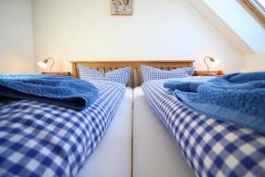 2 Betten in einem Zimmer mit blauen und weißen Schecks in der Unterkunft Gutshof Dubnitz Gutshof Dubnitz -Ferienwohnung 8 " Sammy " 