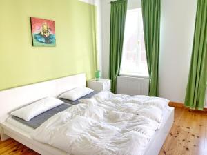 ein weißes Bett in einem Schlafzimmer mit grünen Vorhängen in der Unterkunft Sassnitz - Seaside Appartements Seaside Appartements, "Green" in Sassnitz