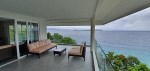 Pinamihagan的住宿－Luxury 3 Bed, 2 Bath Apartment with Stunning Panoramic Sea View, Private Beach，阳台配有沙发和椅子,享有海景。
