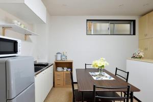 a small kitchen with a wooden table and a dining room at Keimei Guest House in Osaka