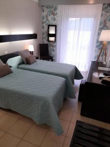 a bedroom with two beds and a desk at Hôtel Beach in Propriano