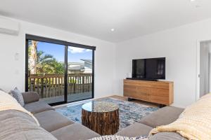 a living room with a couch and a tv at Tuturu Bliss - Ruakākā Holiday Home in Ruakaka