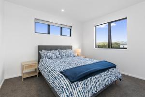 a white bedroom with a bed and two windows at Tuturu Bliss - Ruakākā Holiday Home in Ruakaka