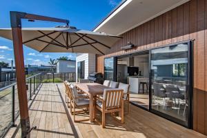 une terrasse avec une table en bois et un parasol dans l'établissement Tuturu Bliss - Ruakākā Holiday Home, à Ruakaka