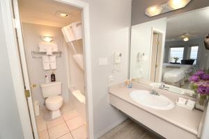 uma casa de banho com um lavatório, um WC e um espelho. em Casa Grande Inn em Qualicum Beach