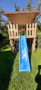 a wooden bench with a blue slide in the grass at Apartma Dana-Brinjtesa in Jesenice
