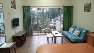 a living room with a blue couch and a balcony at Apartment Teluk Batik in Lumut