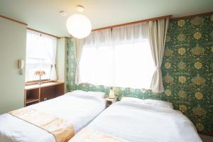 Duas camas num quarto com uma janela em 一棟貸切 Cozy inn Saki -Family & Cyclists Welcome - em Matsumoto