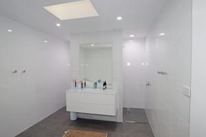 Baño blanco con lavabo y espejo en Boomerang en Sussex inlet