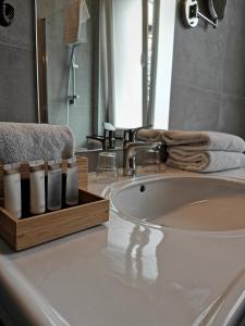 a bathroom with a sink and a tub and a mirror at Hotel de Flandre Ghent in Ghent