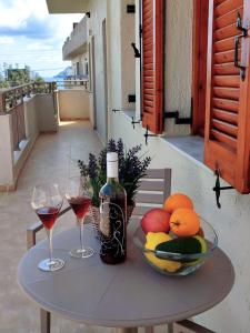 a table with a bowl of fruit and two glasses of wine at Superior Savvas Apartments by the sea in Agia Pelagia