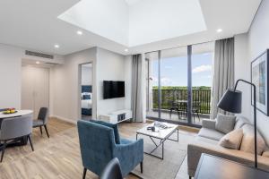 a living room with a couch and chairs and a tv at Meriton Suites Coward Street, Mascot in Sydney