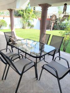 a glass table and four chairs on a patio at HERMOSA CASA EN CUERNAVACA: JARDÍN DEL LAGO in Cuernavaca