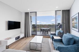 a living room with a couch and chairs and a tv at Meriton Suites Coward Street, Mascot in Sydney