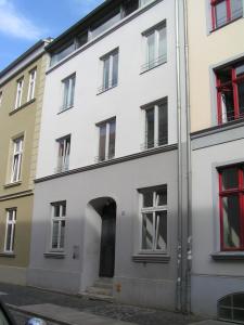 einen Außenblick auf ein weißes Gebäude mit roten Fenstern in der Unterkunft Ferienwohnungen Langenstraße - Altstadt in Stralsund