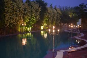 a swimming pool at night with lights and trees at WelcomHeritage Ranjitvilas in Amritsar