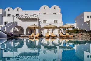 a pool with chairs and umbrellas in front of a building at Villa Thiranthemis in Fira