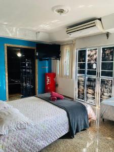 1 dormitorio con 1 cama y TV en la pared en Suites Moreninha, en Río de Janeiro